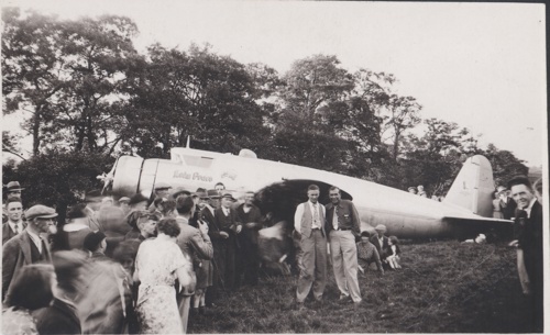 Ffotograff du a gwyn o dorf yn ffurfio o amgylch awyren (y Lady Peace), gyda dau ddyn yn y blaen ac yn y canol.