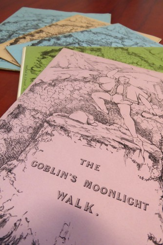 Nifer o gopïau a chloriau lliwiau amrywiol "The Goblin’s Moonlight Walk" ar daen ar fwrdd pren.