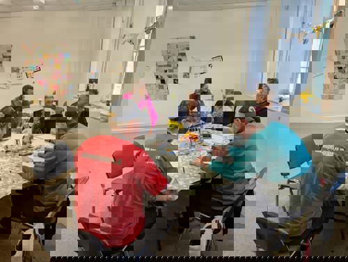 Grŵp o bobl o amgylch bwrdd yng nghanolfan gynnes Caerfyrddin